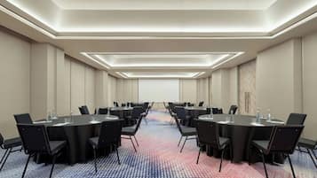 A conference room with a long table, black chairs, and a patterned carpet.