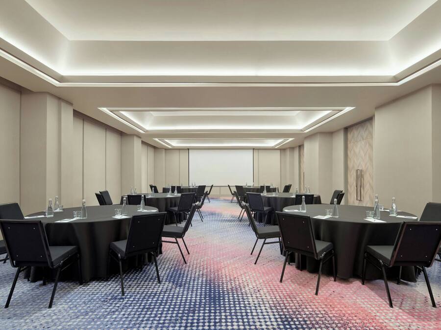 A conference room with a long table, black chairs, and a patterned carpet.