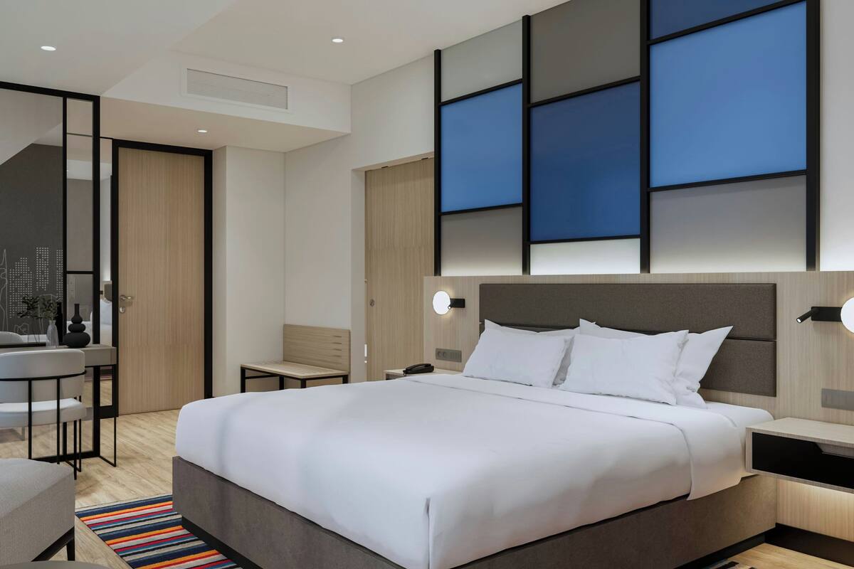 A modern hotel room with a large bed, bedside tables, a desk, and a chair.