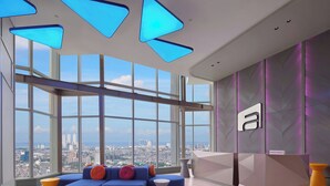 A modern hotel lobby with a large window, a reception desk, and a blue sectional sofa.