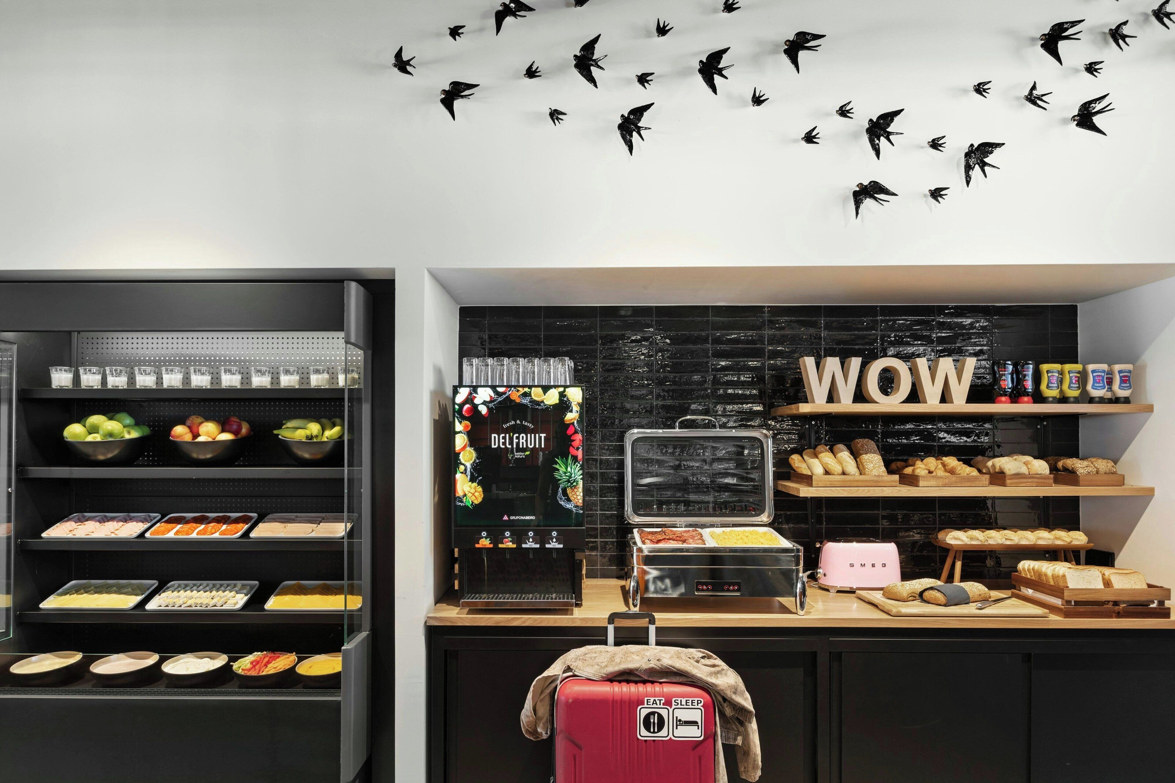 Una barra de desayuno con diversas opciones de comida y una pared con un cartel que dice 'WOW'.