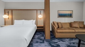 Een hotelkamer met een groot bed, een bruine bank en een schilderij aan de muur.