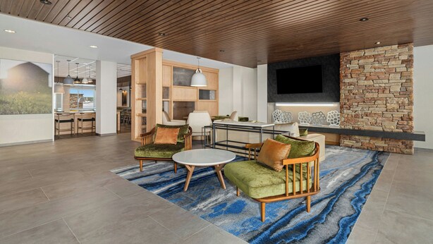 Een ruime woonkamer met een houten plafond, een stenen openhaard en een grote flatscreen-televisie.
