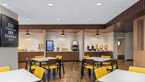 Een modern restaurant met houten details, witte betegelde muren en gele stoelen.