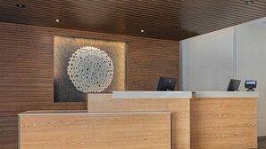 Een modern ontworpen receptiebalie, met een houten afwerking en een groot, rond decoratief element aan de achterwand.