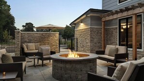 Ein Patio mit einem Steinkamin, umgeben von Korbmöbeln und einer Pergola.