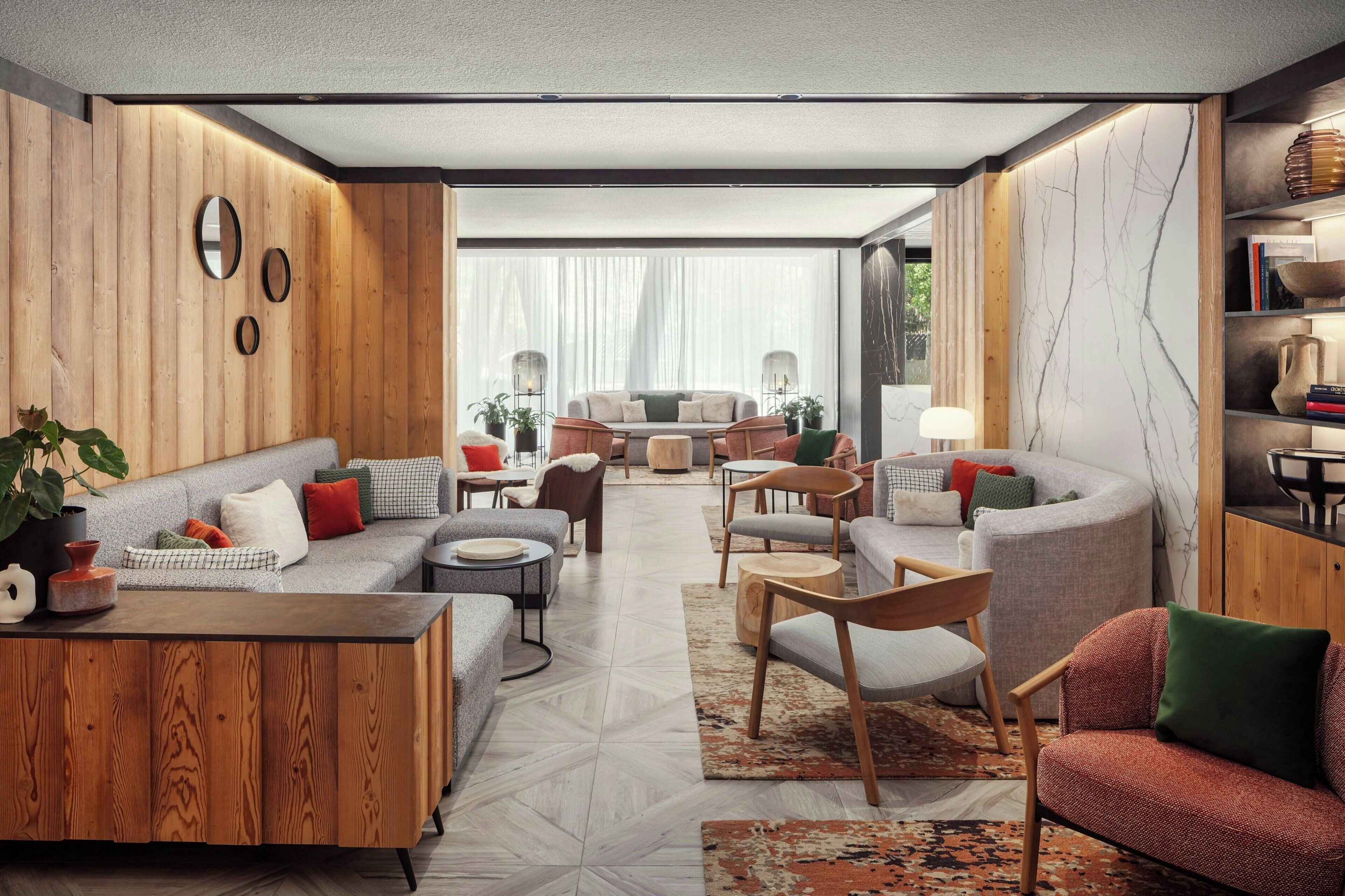 A modern living room with a sofa set, coffee table, and chairs. There is a bookshelf with books and decorative items.