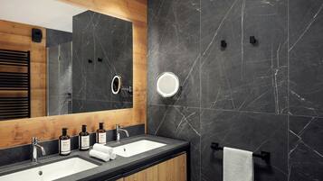 A modern bathroom with two sinks, a large mirror, and a towel rack.