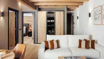 A modern living room with a sofa, cushions, a coffee table, and a dining area with a chair and a plate of food.