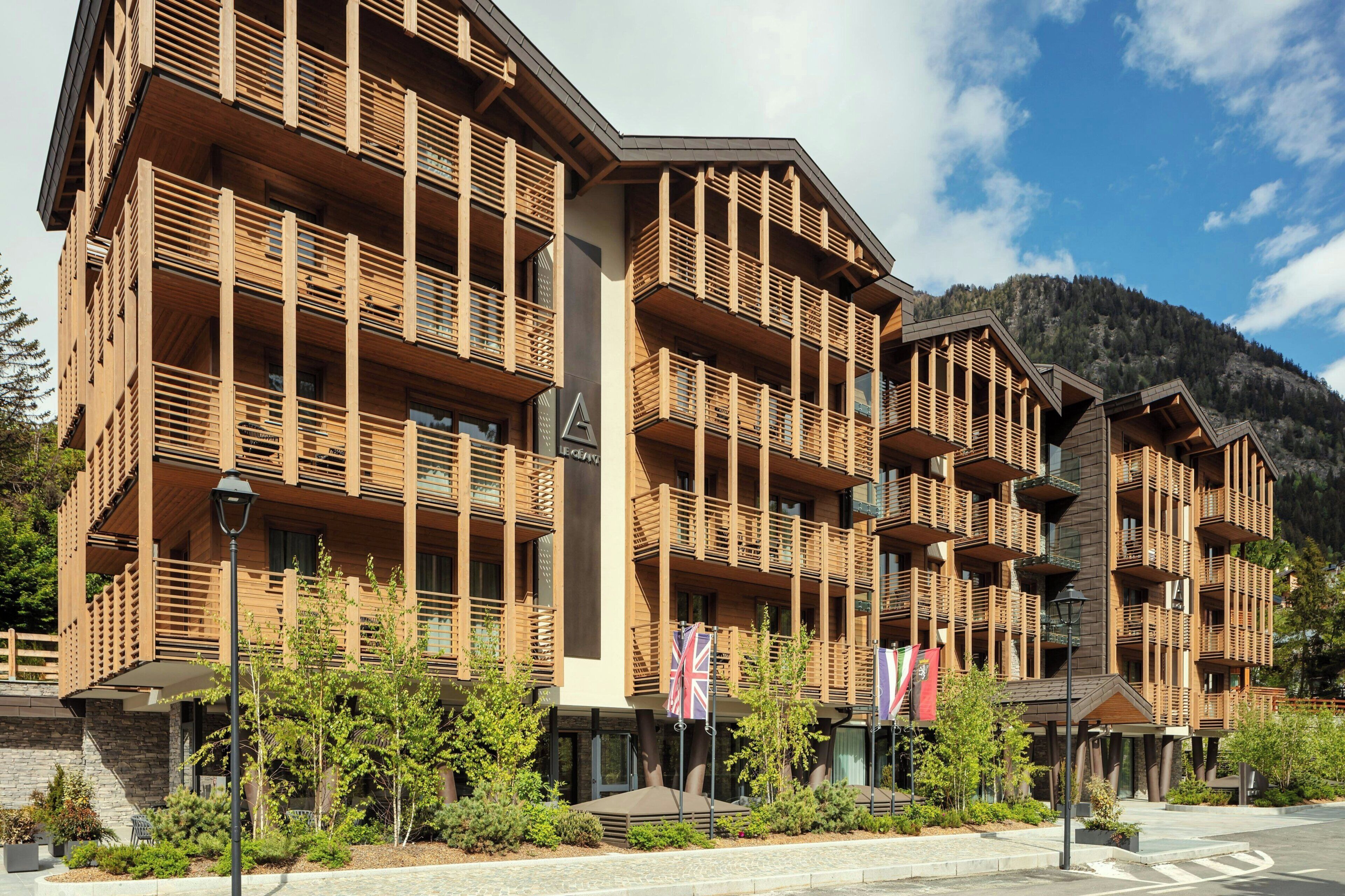Un immeuble à plusieurs étages doté de balcons, d’une façade en pierre et de drapeaux.