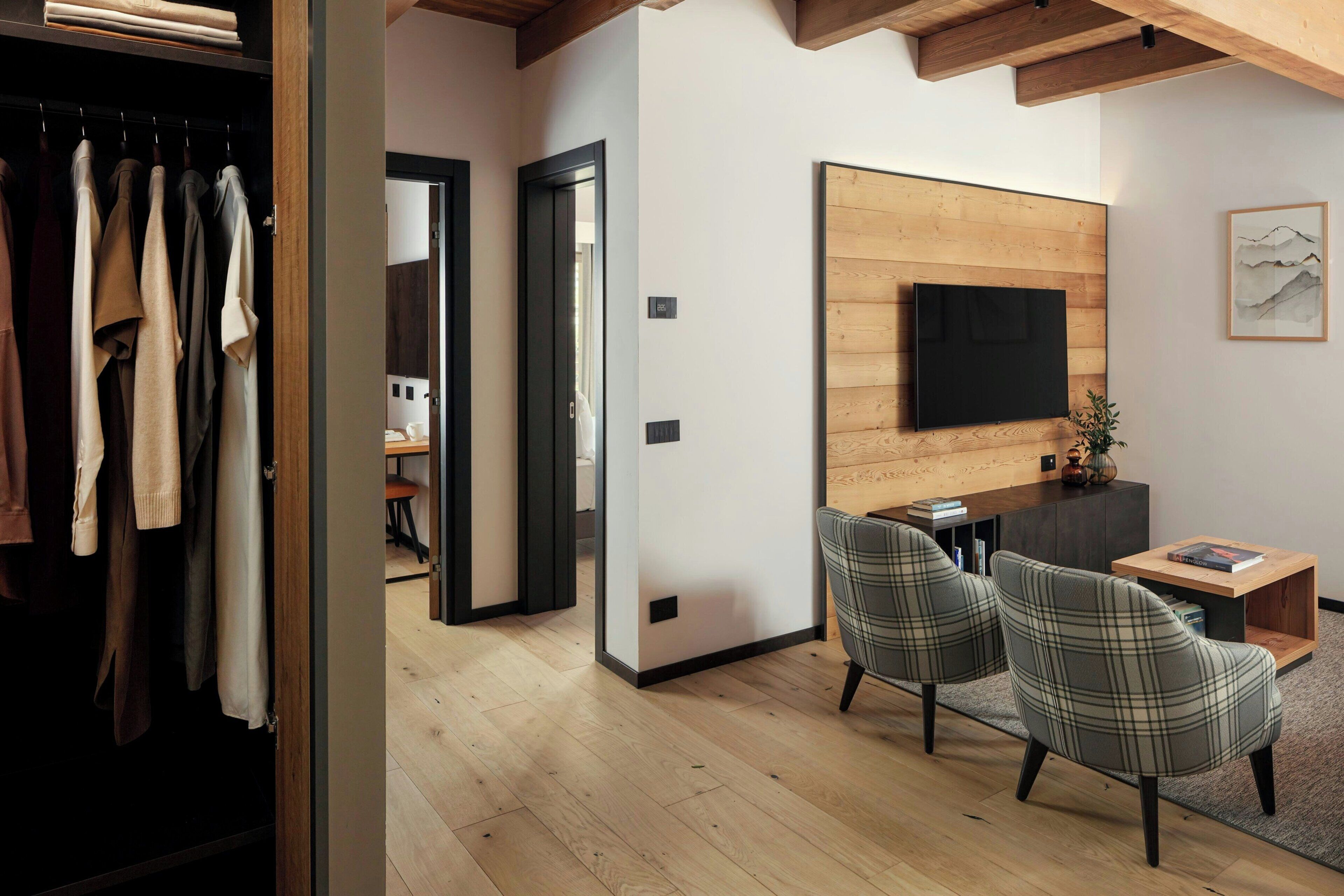 A modern living room with a flat-screen TV, plaid chairs, and a wooden coffee table.