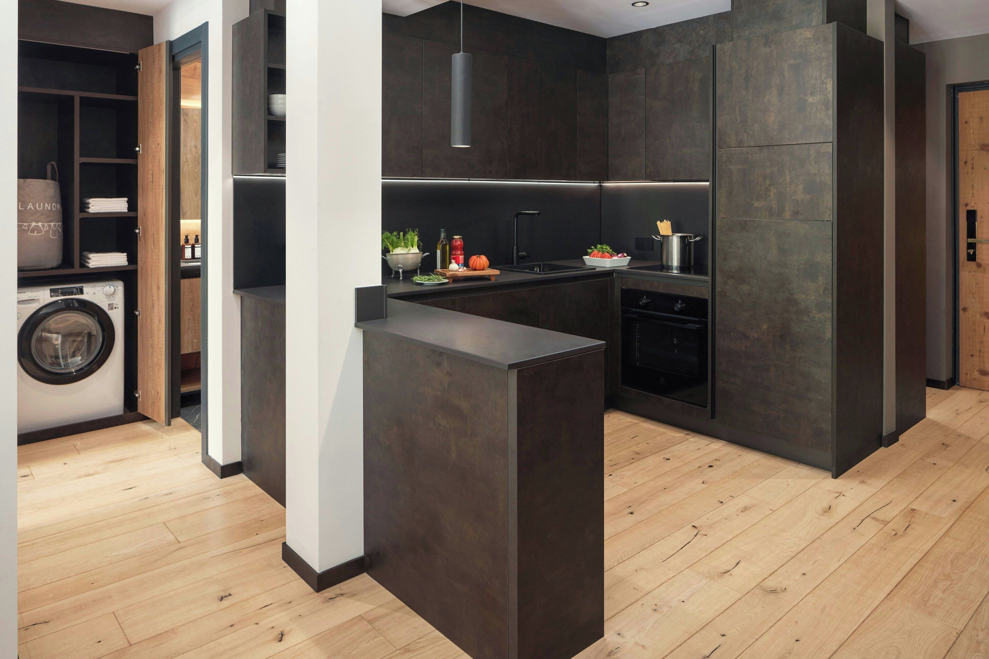 Cocina moderna con armarios oscuros, una isla central y lavadora integrada.
