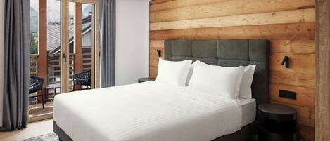 A modern bedroom with a large bed, wooden panel walls, and a view of a balcony.