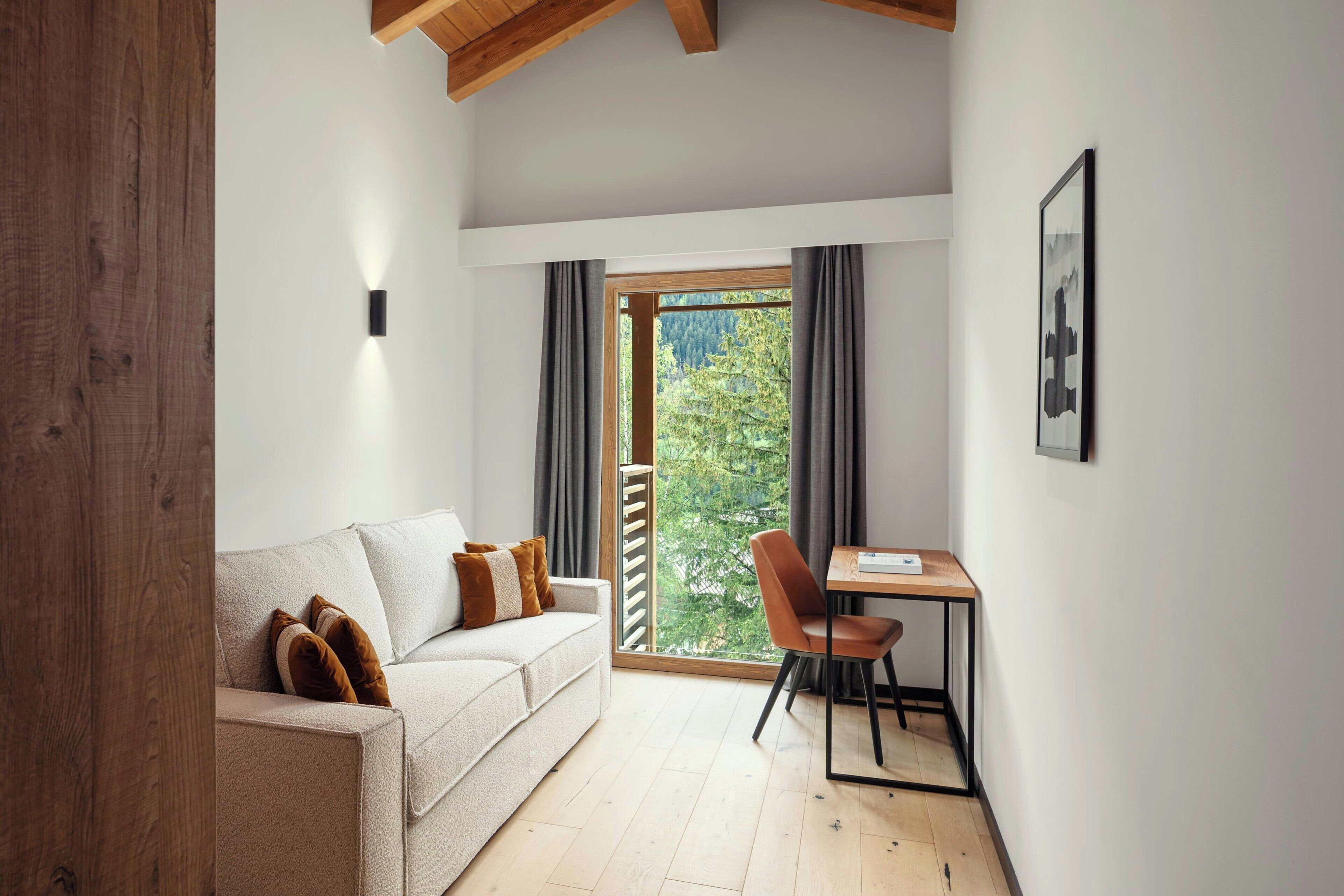A cozy room with a sofa, a chair, a small table, and a window with a view of trees.