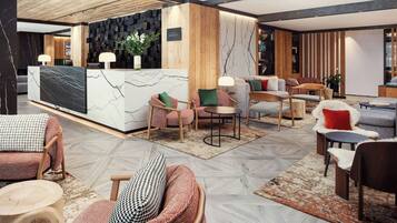 A modern hotel lobby with a reception desk, seating area, and a wooden accent wall.