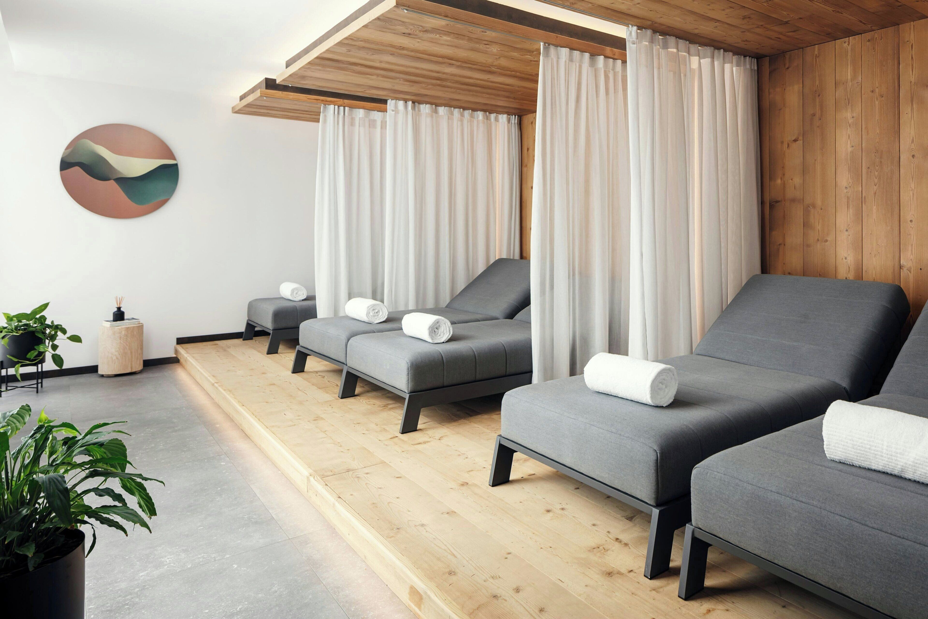 A spa room with three grey massage chairs, a wooden floor, and a wall-mounted artwork.