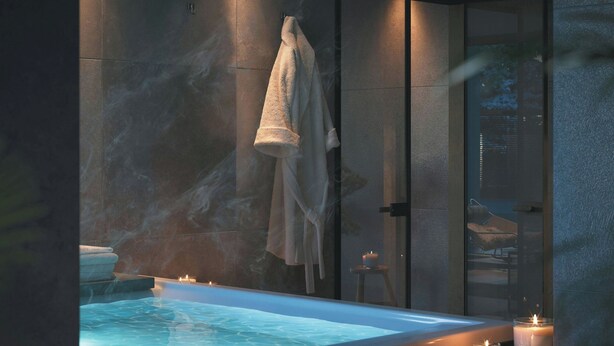 Un spa moderno con una bañera grande, velas y un perchero para toallas.
