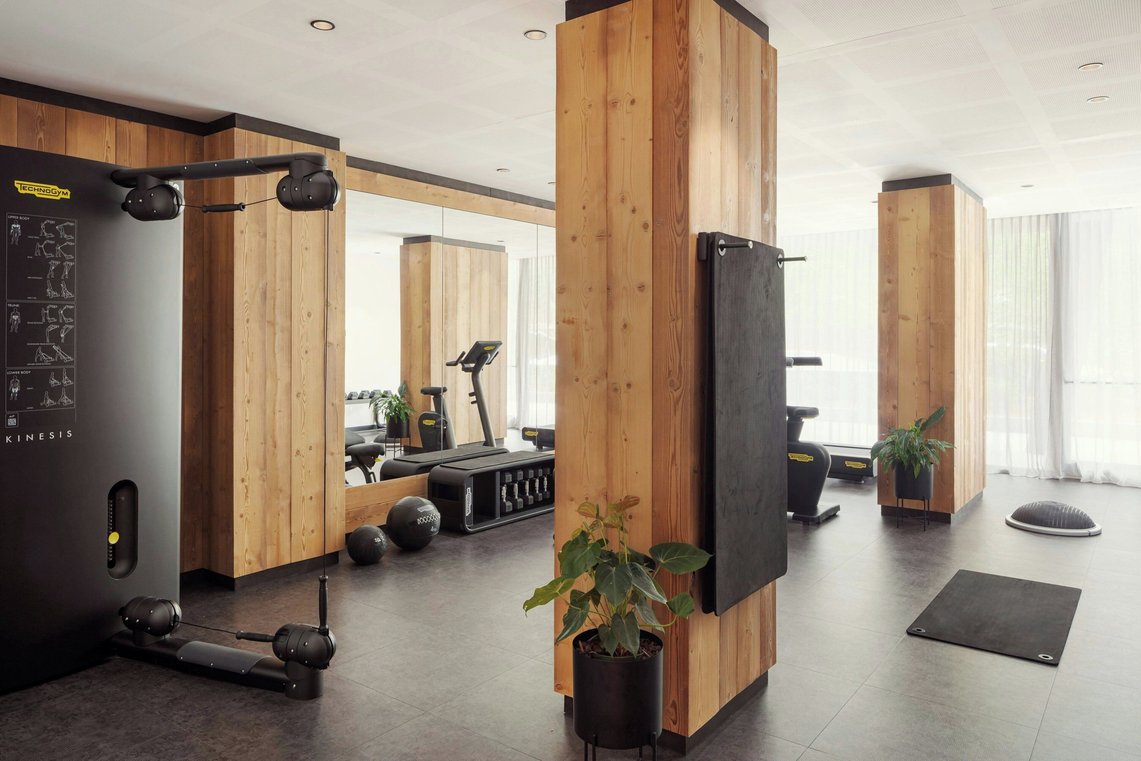A modern gym with wooden accents, exercise equipment, and a mirror.