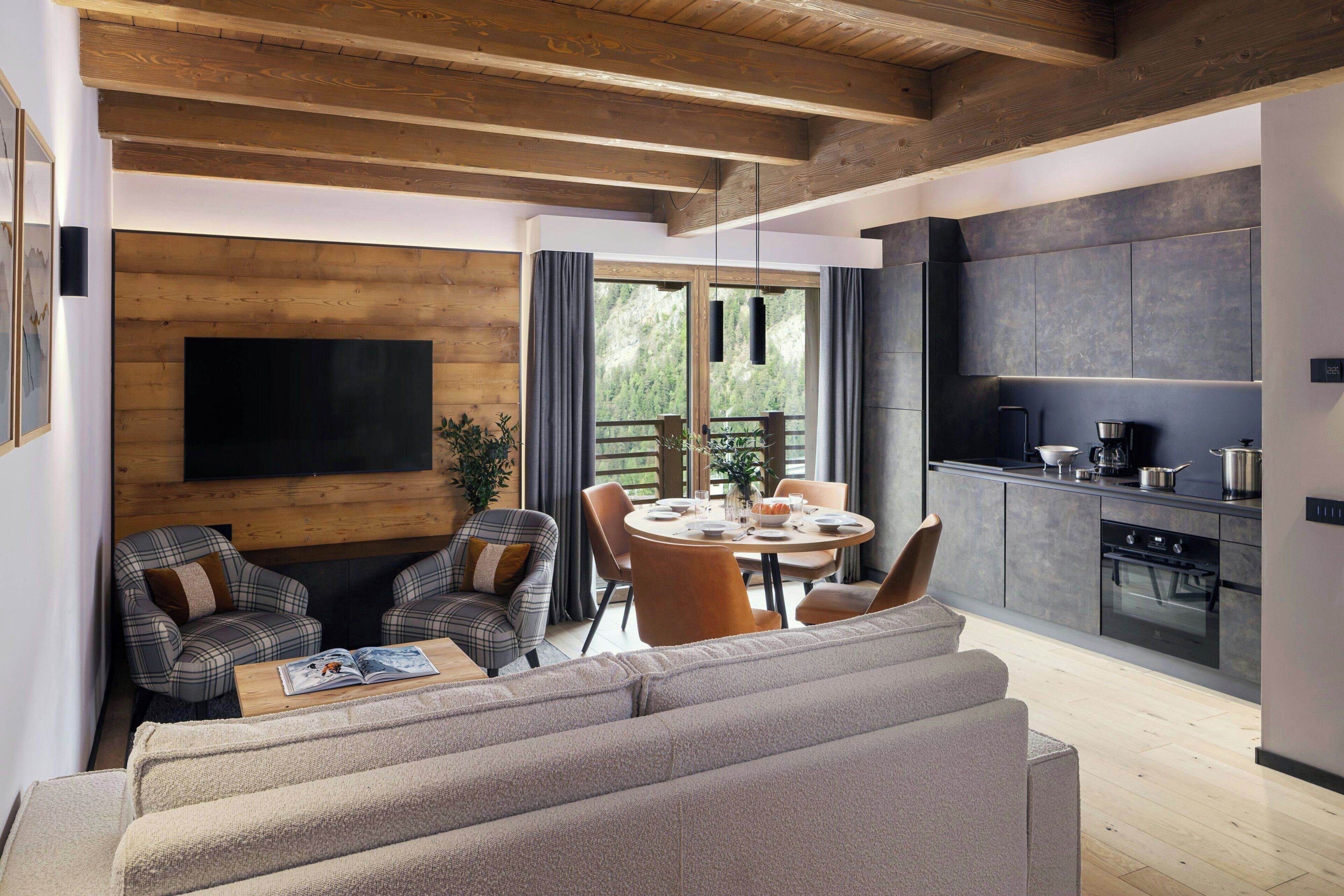 A modern living room with a sofa, a dining table with chairs, and a kitchen area with a stove and cabinets.