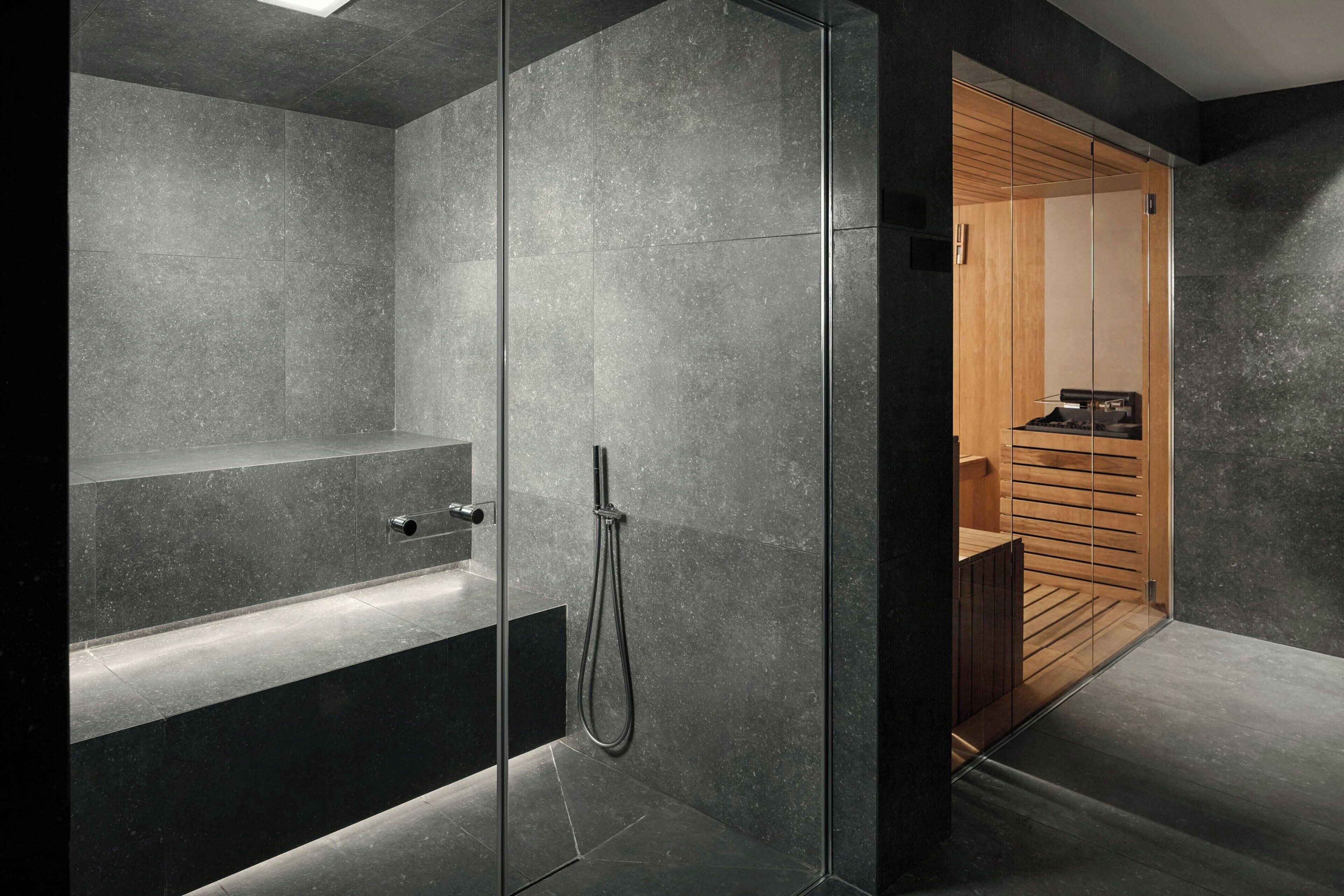 Un baño moderno con ducha de vidrio, banco integrado y tocador de madera.