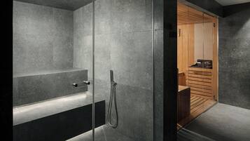 Un baño moderno con ducha de vidrio, banco integrado y tocador de madera.