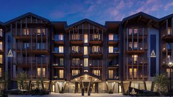 A multi-story hotel with balconies, a central entrance, and a landscaped area.