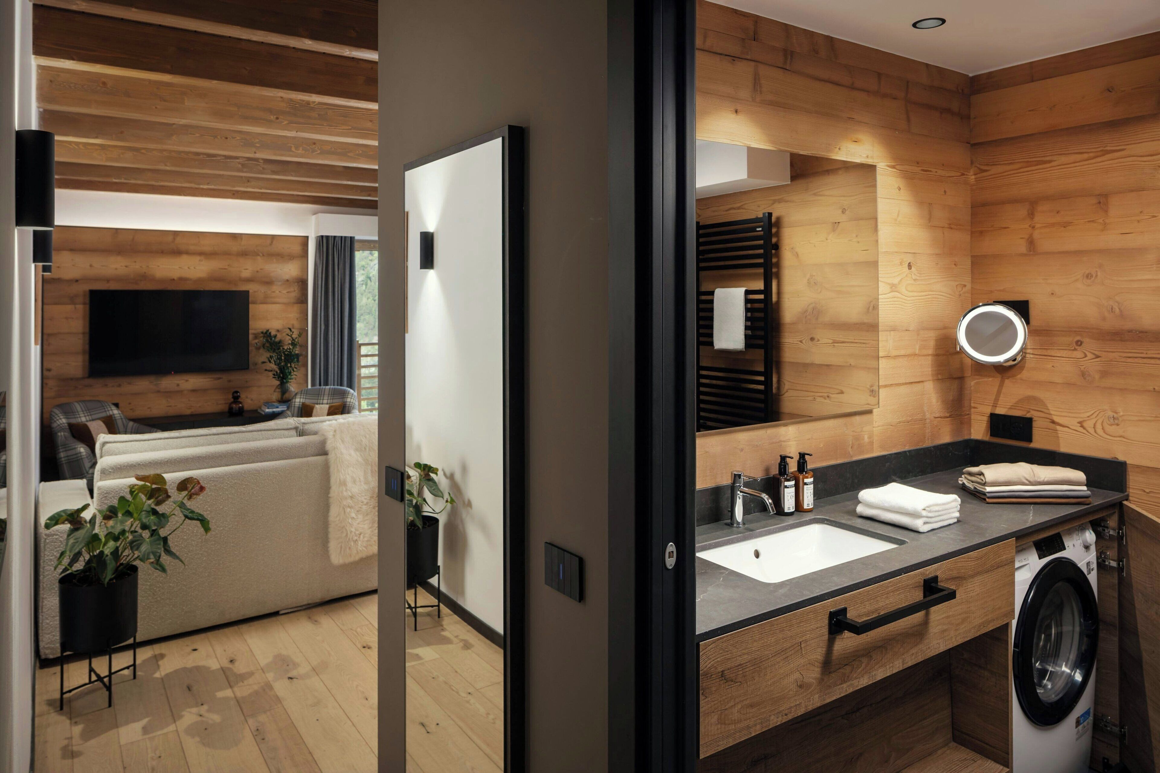 Une salle de bain moderne avec un intérieur en bois, un lavabo, un miroir et un lave-linge.