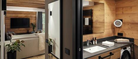 A modern bathroom with a wooden interior, a sink, a mirror, and a washing machine.