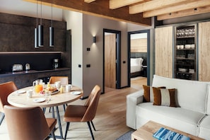 A modern living space with a dining area, a sofa, and a kitchen. - Le Géant, Courmayeur, Apartments By Marriott Bonvoy (Courmayeur)