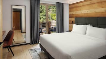 Una habitación de hotel moderna con una cama grande, un escritorio con silla, y un balcón con mesa y sillas.