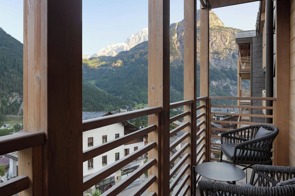 Ein Balkon mit Holzbalkonen, Korbmöbeln und Blick auf die Berge.