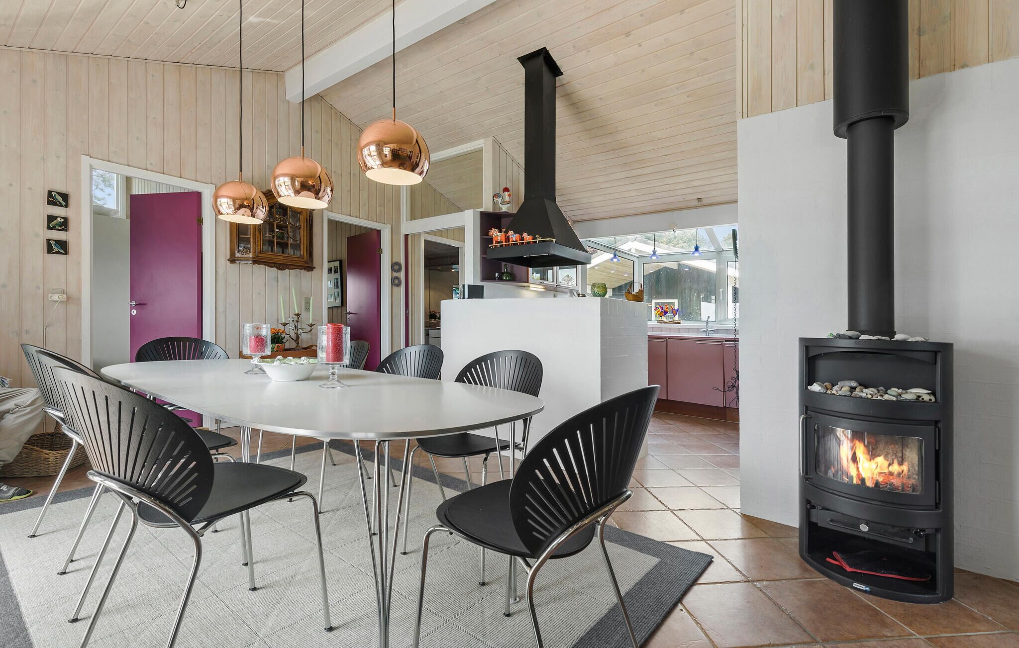 Een moderne keuken met een centraal eiland, zwarte stoelen en een houtkachel.