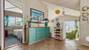 A cozy room with a teal cabinet, a painting of a seascape, and a small table with a lamp and flowers. - 3 bedroom lovely home in Knebel (Knebel)