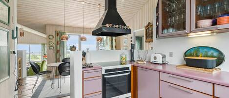 A kitchen with pink cabinets, a black range hood, and a white stove.