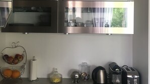 A modern kitchen with stainless steel appliances, a window with a view, and a countertop with various items. - Quiet house in Vernon (Vernon)