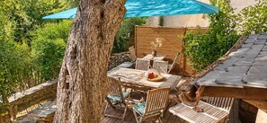 An outdoor patio with a table and chairs, a wooden fence, and a tree. - LATU CORSU – Cosy studio for 2 (ERSA)