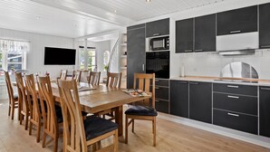 Et moderne køkken med sorte skabe, et træspisebord og et fjernsyn monteret på væggen.