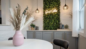 A modern kitchen with a white wall, grey cabinets, and a neon 'Good Vibes' sign. - SunSuite - 6 Min. Walk to Trains - Summer Special! (Jersey City)