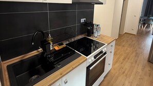 A modern kitchen with black and white cabinetry, a black range hood, and a wooden countertop.