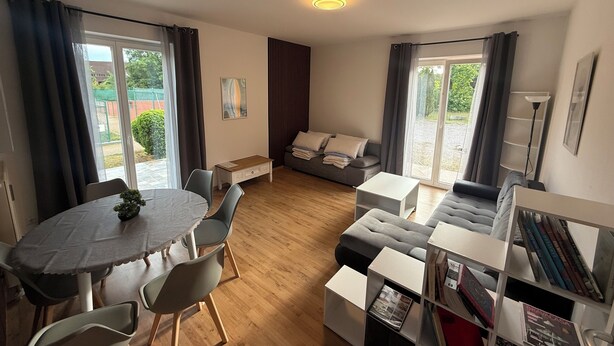 A modern living room with a dining area, a sofa, a bookshelf, and a small table.