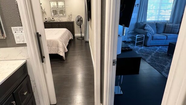Een slaapkamer met een bed, nachtkastje en een dressoir. Er is een raam met gordijnen en uitzicht op de omgeving.