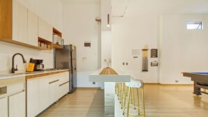 A modern kitchen with a central island, bar stools, and a view of the living area. - All inclusive tourist accommodation and experiences, 6 bedroom with Jacuzzi (Medellín)