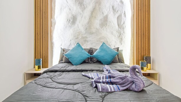 A bed with a striped blanket, two blue pillows, and a purple towel shaped like a swan. - All inclusive tourist accommodation and experiences, 6 bedroom with Jacuzzi (Medellín)