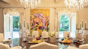 A formal dining room with a large table set for a meal, surrounded by chairs, and adorned with a large painting, candles, and a chandelier. - Villa Loretino - Ultimate Luxury in Florence (Comeana)