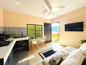 Cocina moderna con comedor, televisor y balcón con vistas.