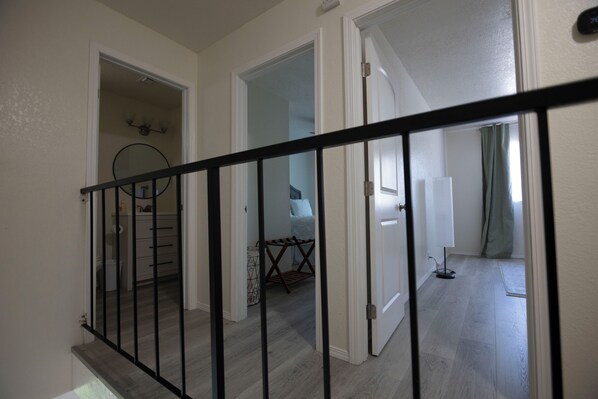 A staircase with a black railing leading to a room with a bed and a window.