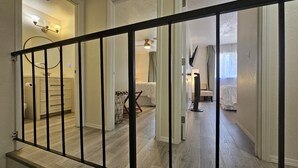 Un pasillo con una escalera, un baño con inodoro y un dormitorio con cama y silla.