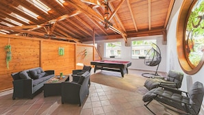 A spacious indoor area with a pool table, wicker furniture, and a hanging chair. - Parl Hotel Bükfürdő (Buk)
