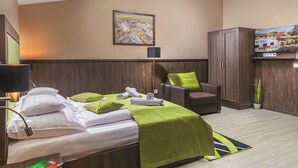 A hotel room with a bed, a chair, a desk, a lamp, a TV, and a framed map on the wall. - Parl Hotel Bükfürdő (Buk)