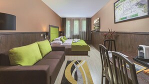 A hotel room with a bed, two sofas, a TV, a desk, and a large window. - Parl Hotel Bükfürdő (Buk)
